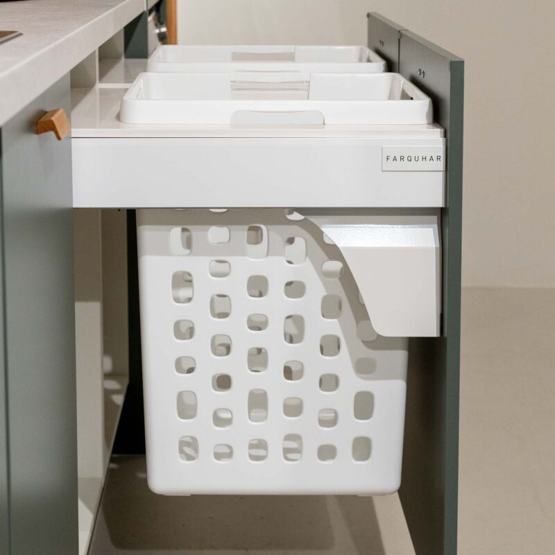 Integrated hampers displayed in a green laundry with light laminate benchtop.