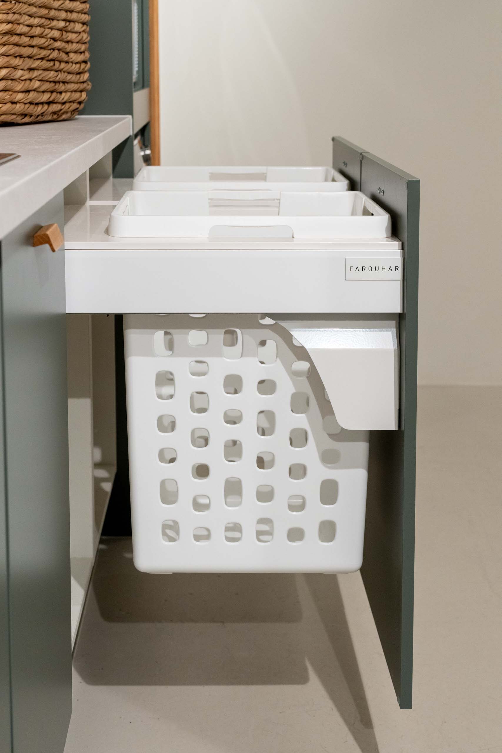 Integrated hampers displayed in a green laundry with light laminate benchtop.