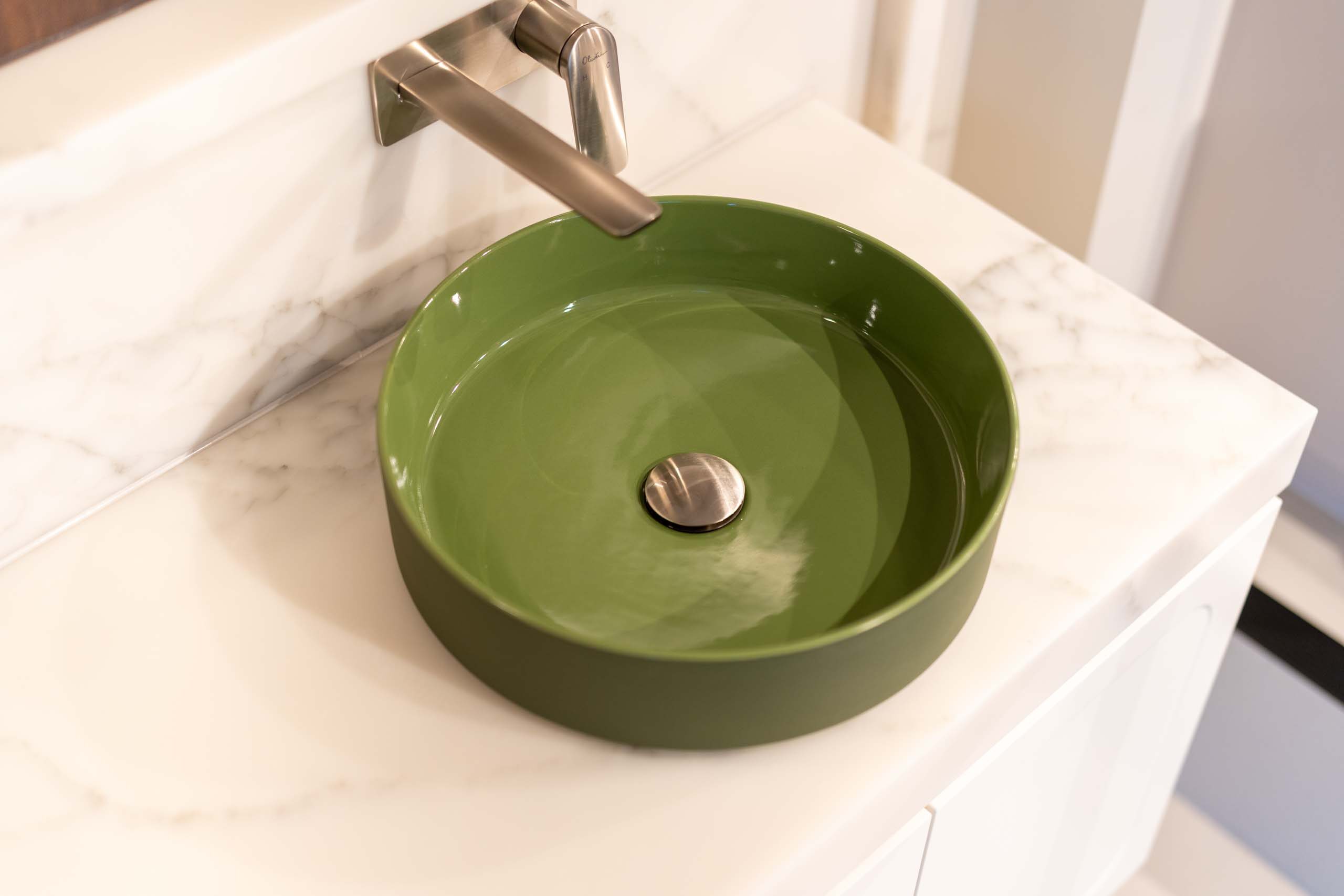 Vanity freaturing a green top mount sink and wall mount stainless steel mixer tap. Installed on a marble benchtop.