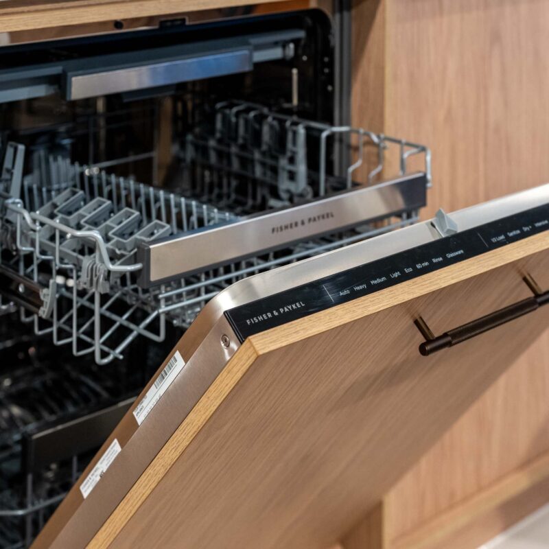 Integrated dishwasher featuring timber grain cabinetry and a bronze handle.