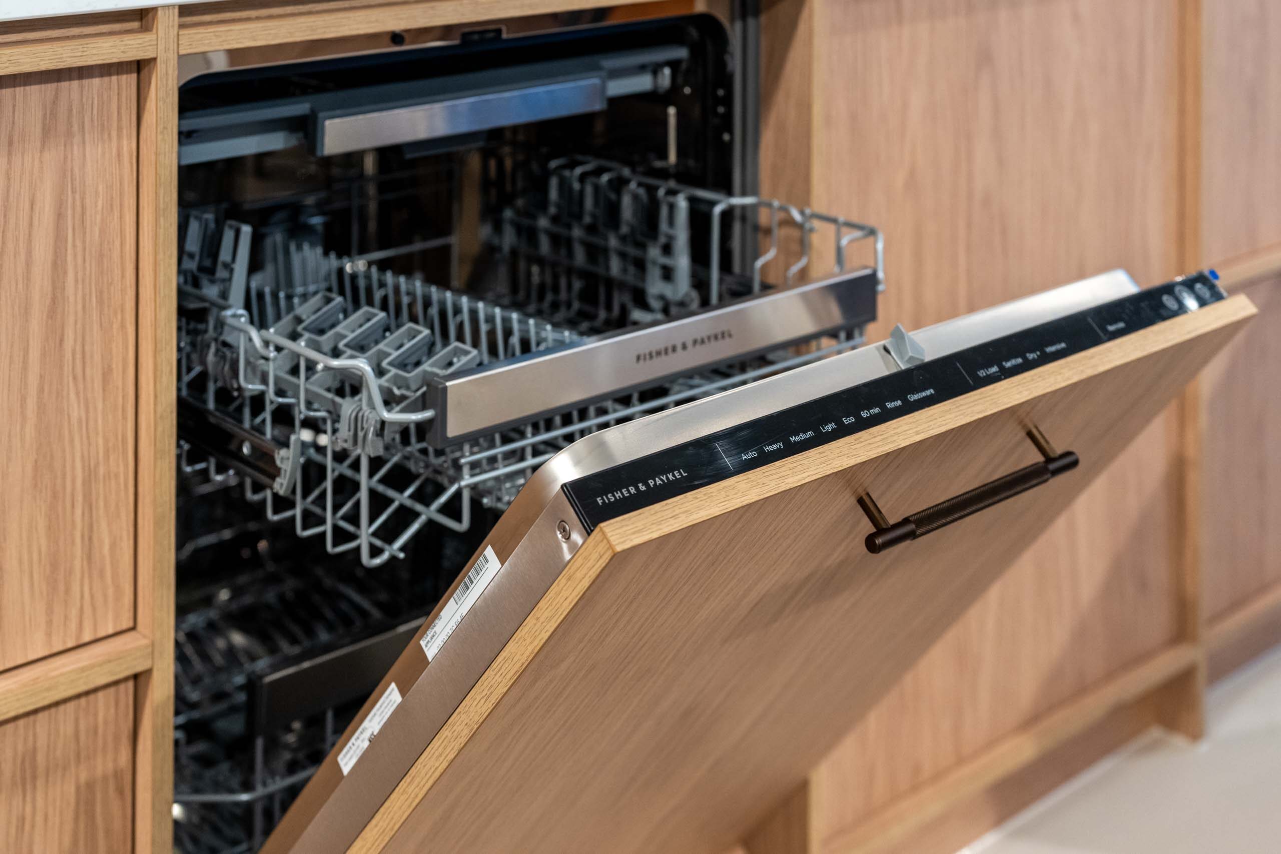 Integrated dishwasher featuring timber grain cabinetry and a bronze handle.