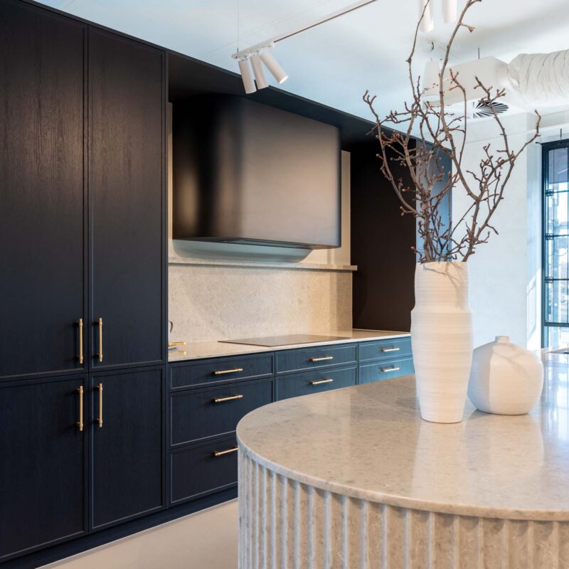 Kitchen display in the Hutt Street Farquhar showroom. Featuring a thin shaker profiled door in timber grain texture graphite colour. Benchtops are Tocco Terranite.